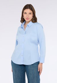 Světle modrá košile na knoflíky s límečkem, dlouhými rukávy a zlatými knoflíky. Hladká látka s mírně přizpůsobeným střihem.