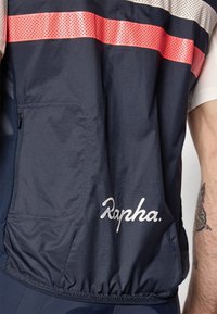 Mornarska biciklistička majica s ružičasto-bijelim prugama, izrađena od laganog materijala. Ima bočnu džep i "Rapha" logotip.
