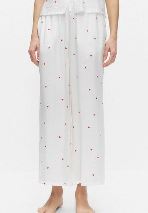 Vita byxor med vida ben i lätt tyg, med små röda hjärtmönster över hela. Mjuk textur, avslappnad passform.
