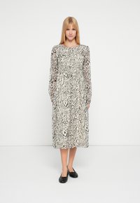 Langärmeliges Kleid in mittlerer Länge mit einem schwarz-weißen Tiermuster. Leichter Stoff, runder Ausschnitt, taillierter Bund und fließender Rock.