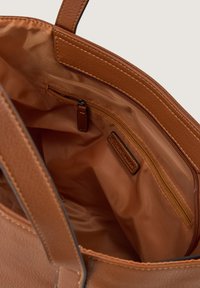 Tan leather tote bag interior with a smooth texture; features a zippered pocket and a fabric lining in a complementary shade.