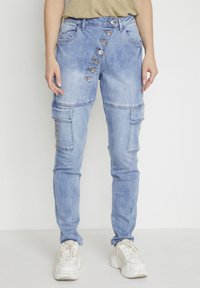 Vaaleansiniset denim-housut, joissa on korkea vyötärö, edessä sarja nappeja, sivutaskut ja slim fit -muotoilu.