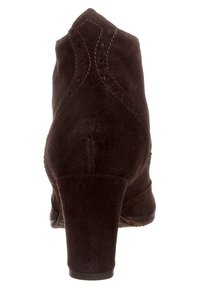 Stivale alla caviglia in suede marrone con punta appuntita, tacco di 3 pollici e cuciture decorative sul retro. Superficie testurizzata con una finitura liscia.