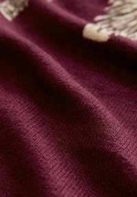 Burgundi tooni tekstuuriga kangas lainelise viimistlusega, millel on sooneline muster ja peened värvimuutused. Pehme ja kudumisega sarnane välimus.