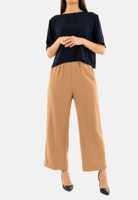 Haut à manches courtes marine associé à un pantalon large beige. Le matériau semble lisse ; le pantalon a un ajustement décontracté et une taille élastique.