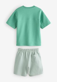 Mintgrøn bomuldst-shirt med korte ærmer og rund hals, parret med matchende mintgrønne shorts med elastisk talje og sidelommer.