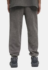 Grå, teksturerede bukser med en afslappet pasform, der har en manchet kant og er parret med sorte, chunky sneakers. Subtile vintage vask detaljer.