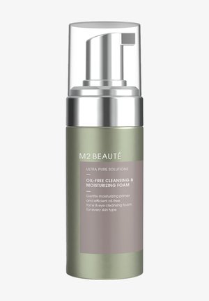 Detergente e idratante schiumoso senza oli, in una bottiglia a pompa di vetro verde ghiacciato e argento, con un'etichetta grigia che descrive l'uso del prodotto e i benefici.