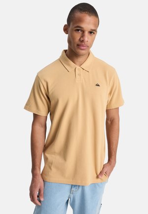 Lichtbeige polo van katoen met een kraag, een drieknopsblouse en een klein donker logo op de borst.