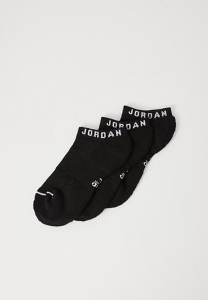 Calcetines negros hasta el tobillo con el texto en blanco "JORDAN" en los puños, fabricados en un tejido suave, con una textura acanalada y una zona de los dedos reforzada.