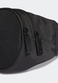 Musta kangaskassi, jossa on kaksi vetoketjullista lokeroa, joka on valmistettu teksturoidusta materiaalista ja jossa on mustat metalliosat.