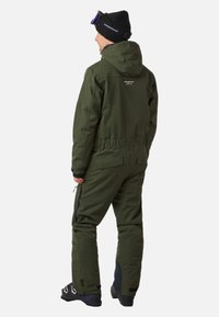 Zielony ocieplany kombinezon narciarski z kapturem, zamkami błyskawicznymi na spodniach i teksturowanym wykończeniem. Posiada regulowany pas oraz wzmocnione panele na nogawkach.