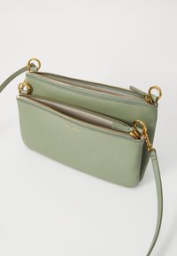 Borsa a tracolla in pelle verde con due scomparti con zip, hardware dorato, finitura texturizzata e tracolla staccabile.