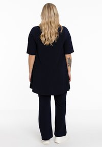 Ensemble deux pièces bleu marine comprenant une tunique longueur genoux à manches courtes et un pantalon à coupe décontractée. Tissu lisse avec une légère brillance.