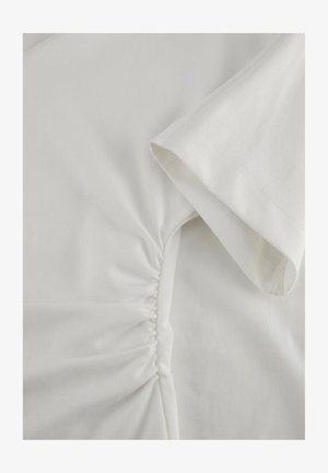 White short-sleeve shirt with ruched detail along the side seam near the underarm area.