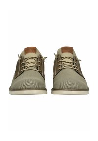 Beige Netzschuhe mit braunen Lederakzenten, Schnürdesign, strukturierten Oberflächen und einer flachen Sohle. Mit einer kontrastierenden, tanfarbenen Fersenschlaufe.