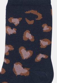 Marineblaue Socken mit einem gemusterten Design aus braunen und hellrosa Herzen, aus einem gerippten Strickmaterial mit einer weichen Textur.
