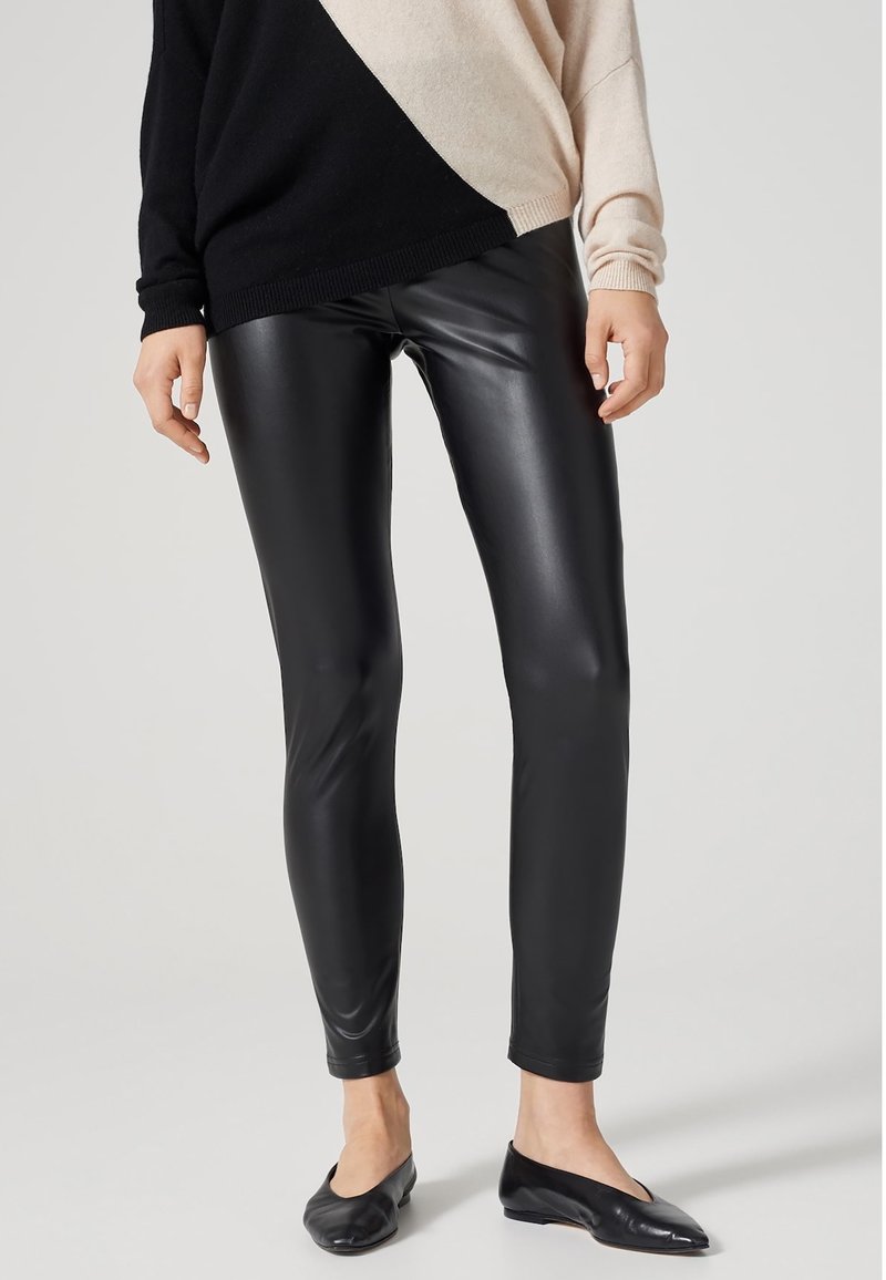 Zwarte nepleer leggings met een slank, aansluitend ontwerp. Glad textuur, hoge taille en enkel-lange snit. Gedeeltelijk gedragen met een zwart en beige trui.