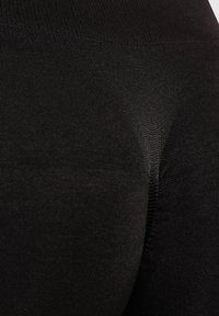Leggings negros con un tejido suave y elástico, que presentan un diseño ajustado y una sutil textura acanalada en toda su superficie.