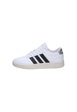 Zapatilla blanca de Adidas con rayas negras, cordones blancos y suela beige, vista de perfil sobre un fondo blanco.