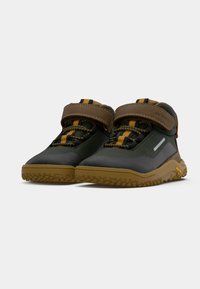Une paire de chaussures de randonnée pour enfants, de couleur vert foncé et marron, avec des accents jaunes, des straps Velcro et des semelles en caoutchouc texturé.