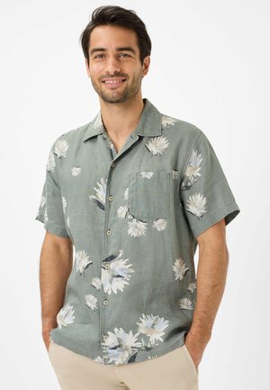 Camicia a maniche corte in tessuto verde chiaro con motivo floreale bianco, dotata di taschino sul petto e chiusura con bottoni.