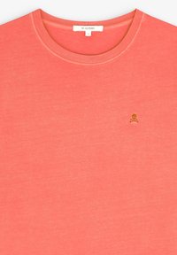 T-shirt in cotone corallo con scollatura rotonda, maniche corte e logo di teschio e ossa incrociate dorato sul petto. Morbido al tatto, design casual.