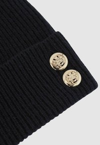 Beanie tricotat navy cu textură canelată, dotat cu două butoane aurii cu designuri intricate pe mansetă.