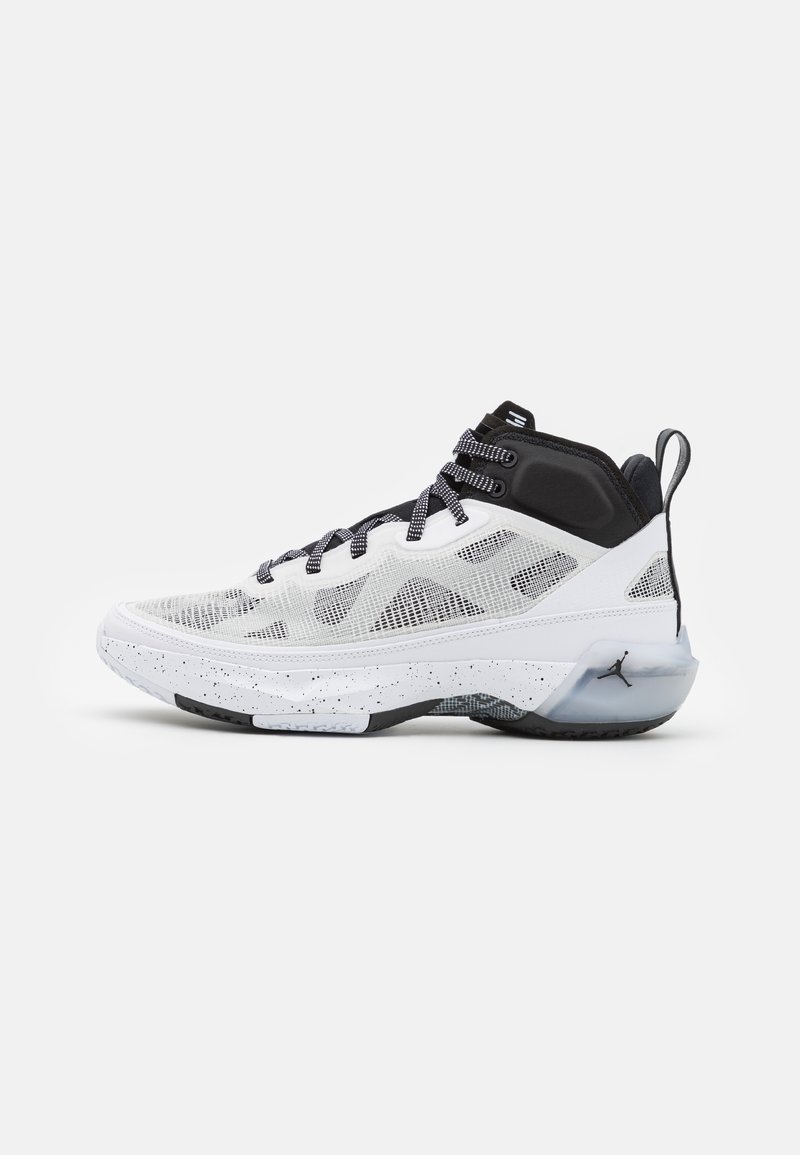 Chaussure de basketball montante blanche et noire avec une tige en mesh, une semelle intermédiaire tachetée, des lacets noirs et un talon translucide avec un petit logo noir.