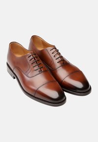 Braune Lederdressschuhe mit einer Kappe, die eine glatte Oberfläche, eine Schnürung und dezente kontrastierende Nähte aufweisen.