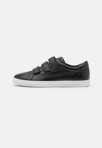Baskets en cuir noir avec trois bandes Velcro, semelle en caoutchouc blanche et texture lisse. Forme simple et moderne avec un branding minimal.