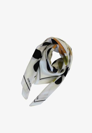 Pañoleta de seda blanca con formas abstractas negras, verdes y naranjas, doblada en un lazo suelto con un borde negro visible y texto en los bordes.