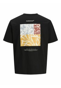 Sort T-shirt med et kvadratisk design, der inkluderer røde, gule og lyse bladmønstre. Tekst trykt nederst.