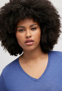 Blauwe V-hals t-shirt gemaakt van zachte, gestructureerde stof. Heeft korte mouwen en een soepele, ontspannen pasvorm rond de halslijn.