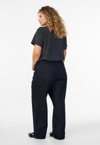Camiseta negra de manga corta y jeans rectos de lavado oscuro. Tejido suave, corte holgado, con bolsillos traseros y detalles de costura mínimos.