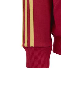 Czerwona bluza z rękawem z prążkowanym mankietem i trzema żółtymi paskami po boku dla dodatkowego efektu. Materiał wydaje się miękki i teksturowany.