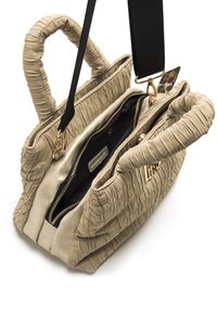 Sac à main en beige texturé avec des détails froncés, deux poignées et une bandoulière noire amovible. Deux compartiments avec des fermetures à glissière dorées.