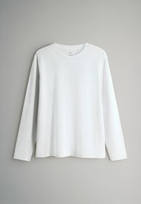 Ilga rankovė balta marškinėliai, pagaminti iš švelnios medvilnės. Turi apvalią iškirptę ir laisvą siluetą, be matomų raštų ar puošmenų.