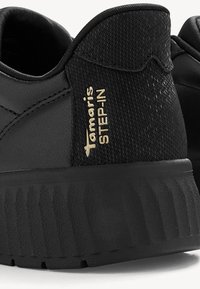 Melnas kedas ar strukturētu auduma virsmu, gumijas zoli un zelta 'Tamaris STEP-IN' zīmolu sānos. Apaļa purngala forma un polsterēta apkakle.