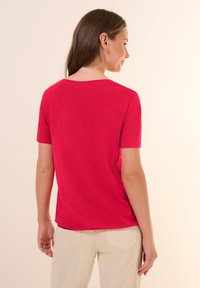 T-shirt rouge à manches courtes en tissu doux et texturé, avec un col rond et un ourlet droit, vu de l'arrière.