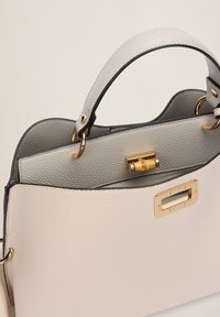 Borsa in pelle di un morbido beige e grigio, con un design strutturato, accessori dorati e una texture liscia con accenti a contrasto.