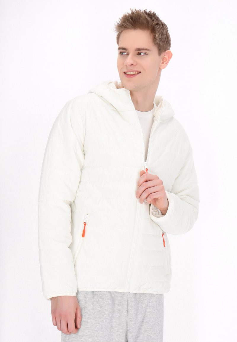Witte donzen jas met een capuchon, voorzien van oranje ritslippen en een gewatteerde textuur. Het model draagt het over een licht shirt en grijze broek.