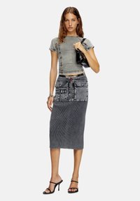 Gray cropped top with short sleeves, paired with a midi pencil skirt featuring a denim pocket detail. Worn with black strappy heels.