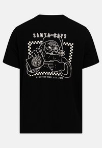 Czarna koszulka z białą grafiką Świętego Mikołaja trzymającego kartkę, z napisem "ŚWIĘTY MIKOŁAJ MÓWI" powyżej oraz w kratkę obramowaniem.