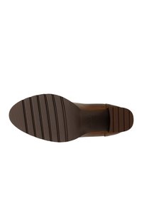 Bruine leren schoen met een gladde bovenzijde en een gestructureerde, bruine rubberen zool. De zool heeft diepe groeven voor grip en stabiliteit.