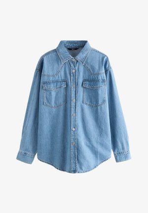 Camisa de mezclilla azul claro con cuello puntiagudo, mangas largas, dos bolsillos en el pecho, botones plateados y dobladillo ligeramente curvado.