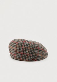 Boné plano xadrez em tons de marrom, verde e vermelho, com um botão em cima, exibido sobre uma superfície branca simples.