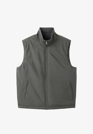 Mörkgrön ärmlös väst, dragkedja framtill, hög krage, två sidofickor, slät textur och minimalistisk design.