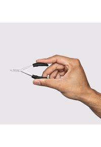 Hand holding small metal nail clippers with black rubber handles against light background.