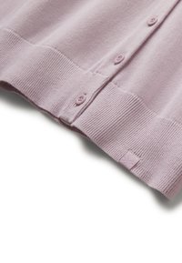 Měkký svetřík z levandulové pleteniny se spodním lemem, třemi viditelnými knoflíky a malou látkovou etiketou na bílém pozadí.